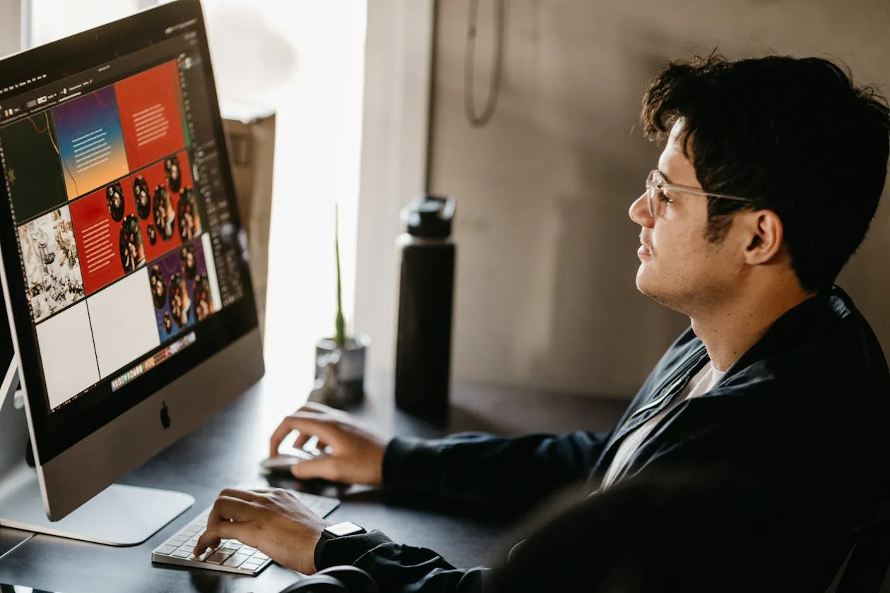 Graphic designer working at a computer with design software on screen in a modern studio