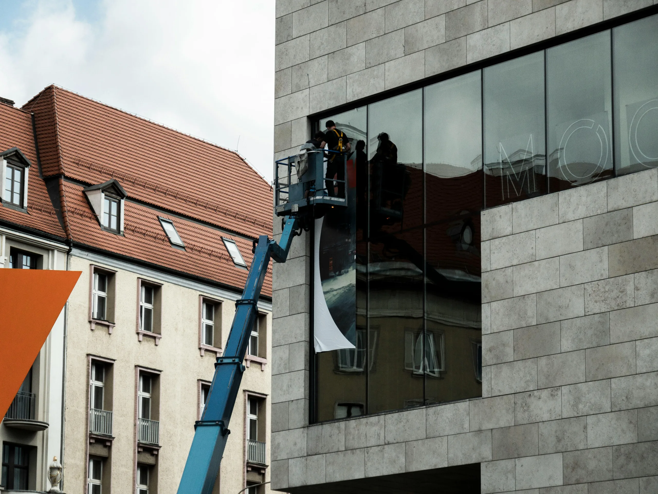 Workers installing large format printed hoarding panel on building facade