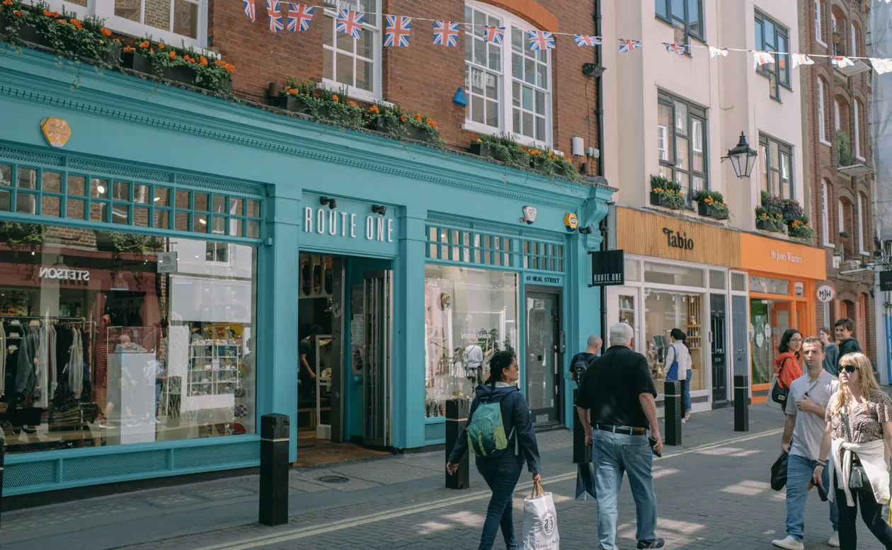 Busy UK shopping street with British flags and vibrant retail store facades with signage