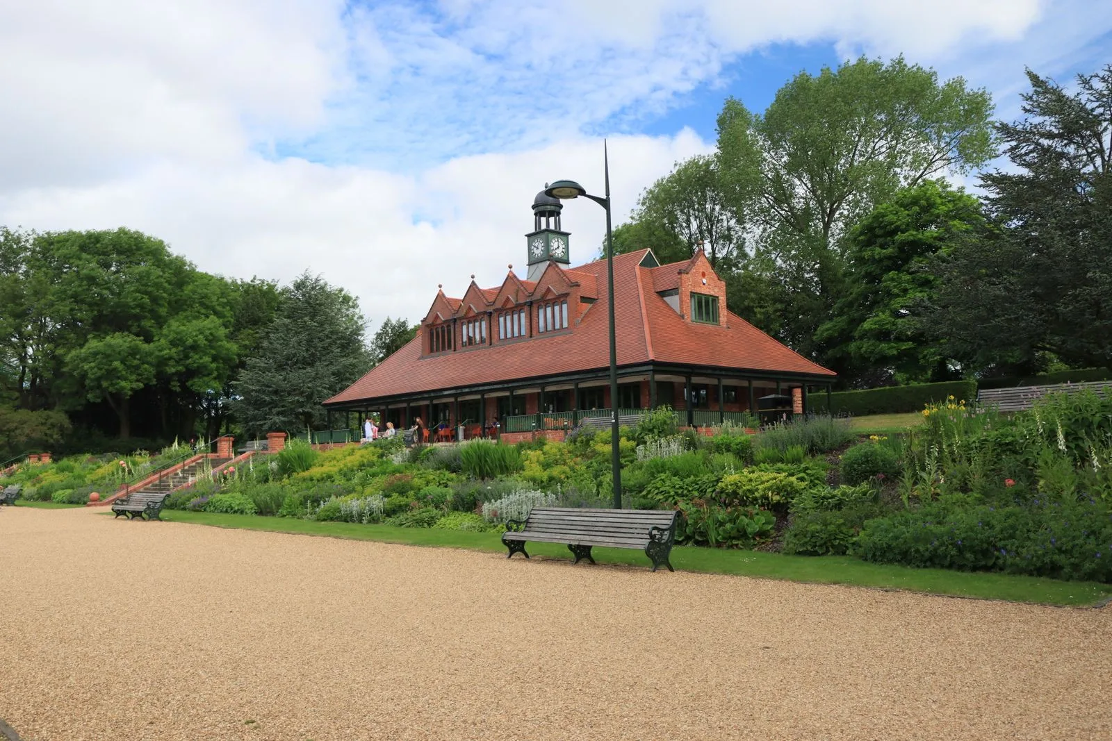 Traditional English pavilion building with clock tower and veranda in parkland setting
