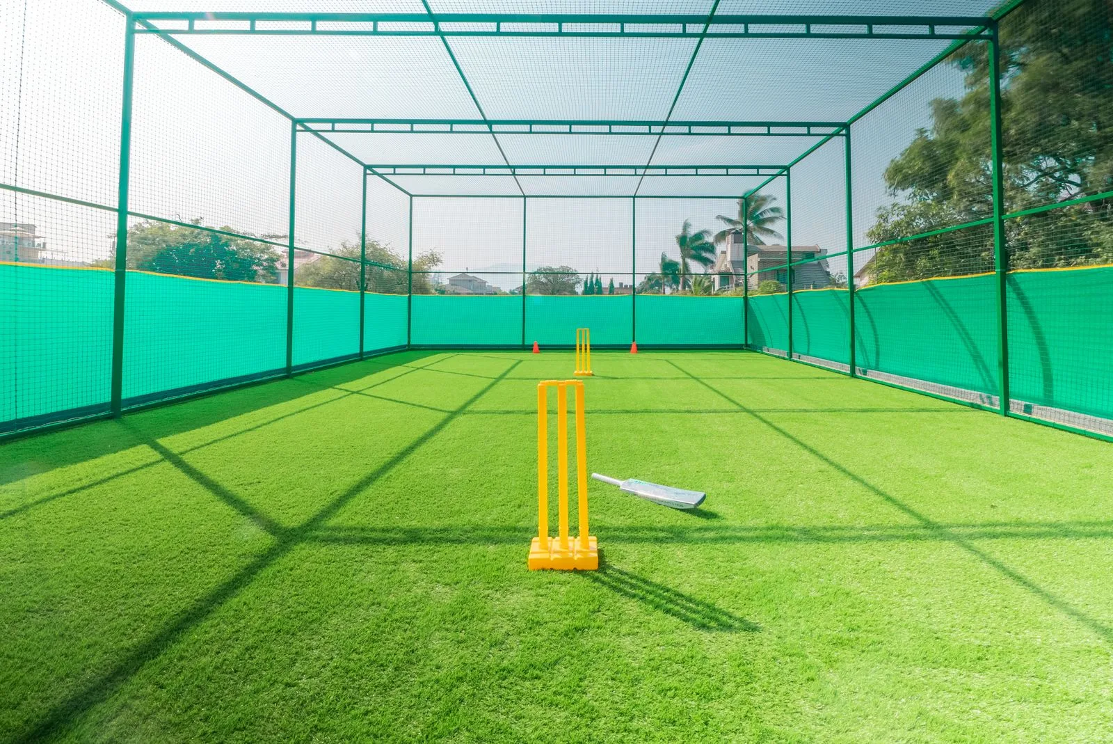 Cricket practice net with stumps and bat on artificial turf