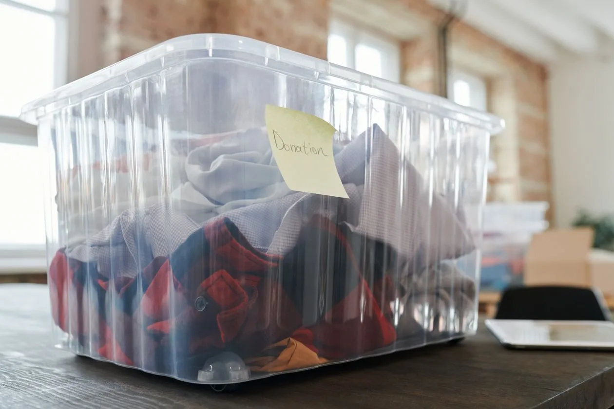 Clear donation box filled with folded clothing