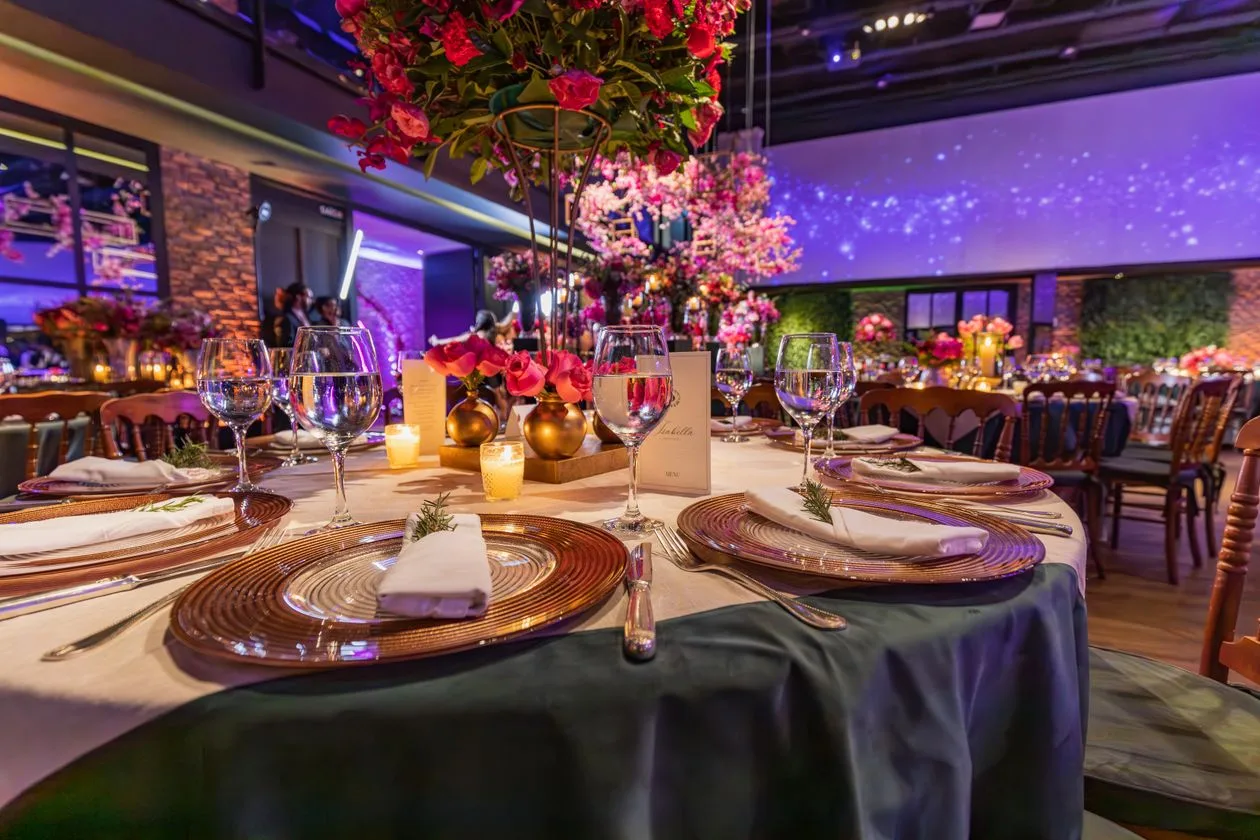 Elegant event table setting with dark tablecloth and floral centrepiece