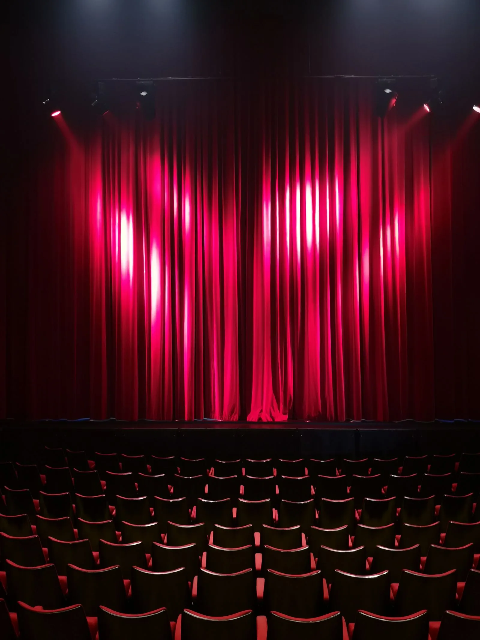 Empty theatre with red curtains and seating ready for a performance