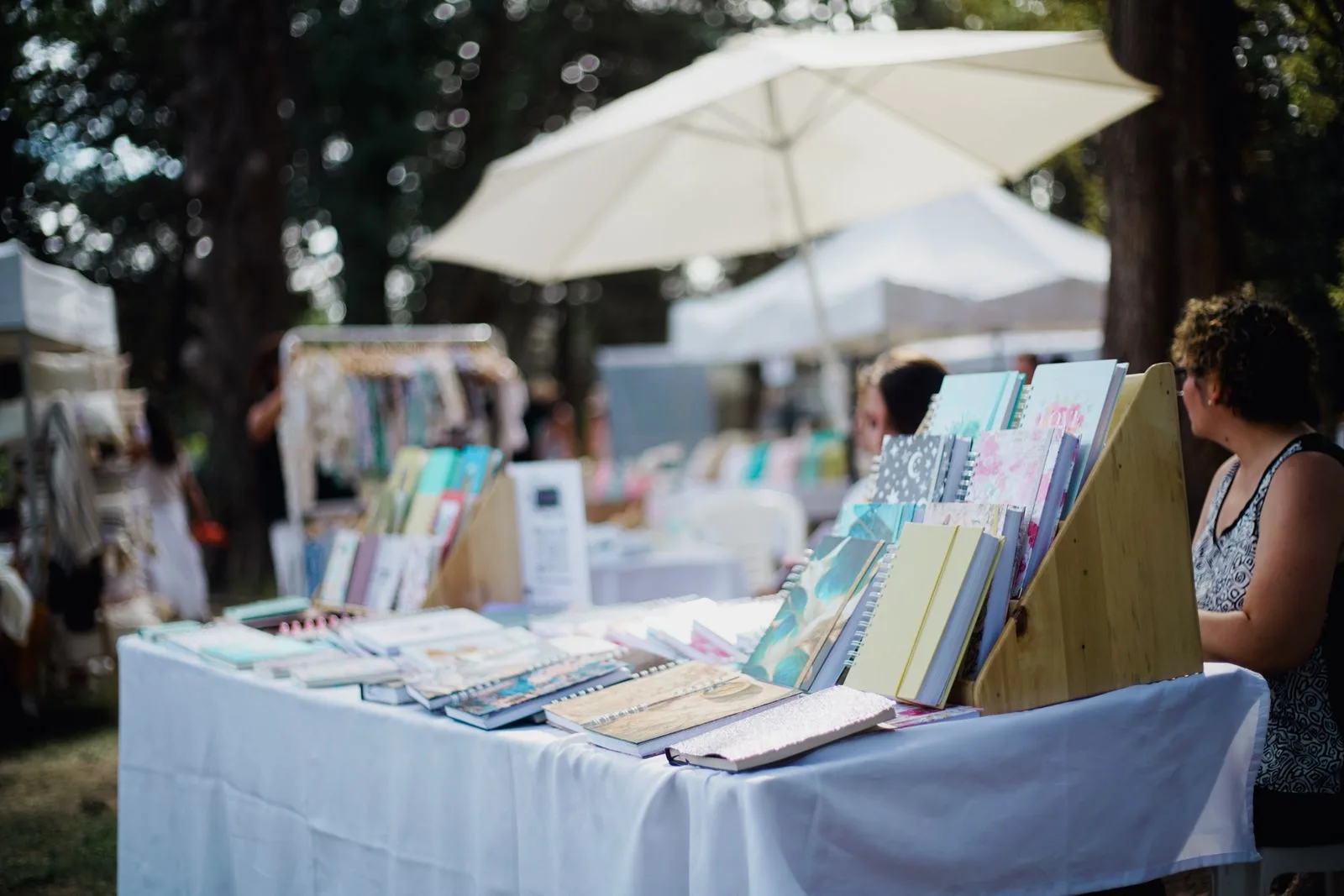 Outdoor market stall table display with visitors browsing