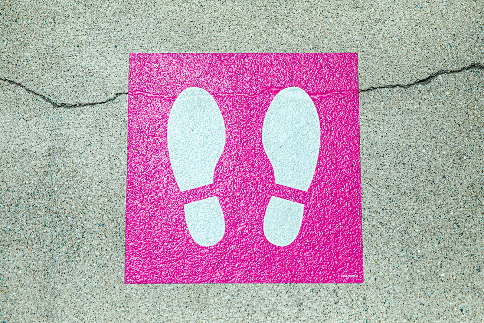 Pink footprint floor graphic on a concrete surface
