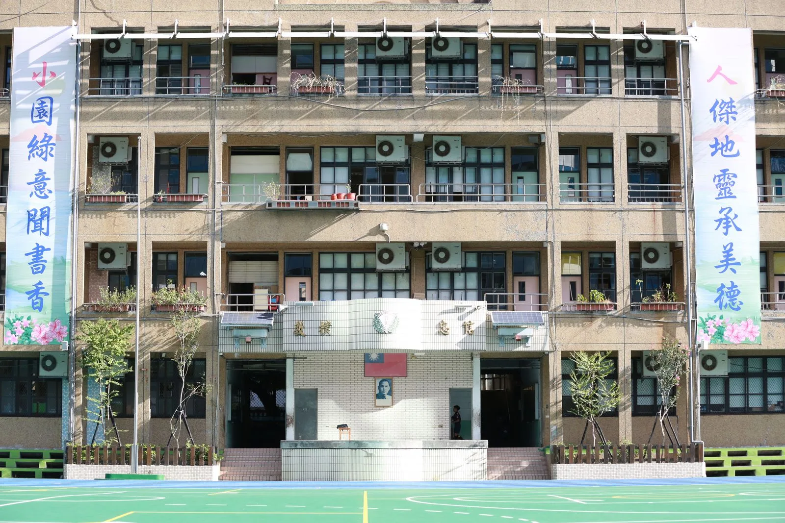 Multi-storey school building exterior with a green courtyard
