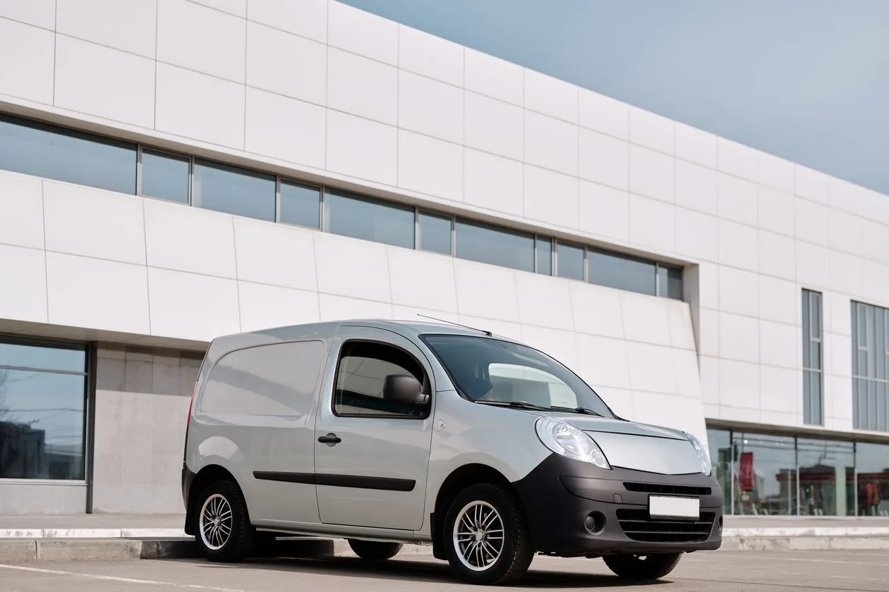 Silver panel van parked outside a modern building