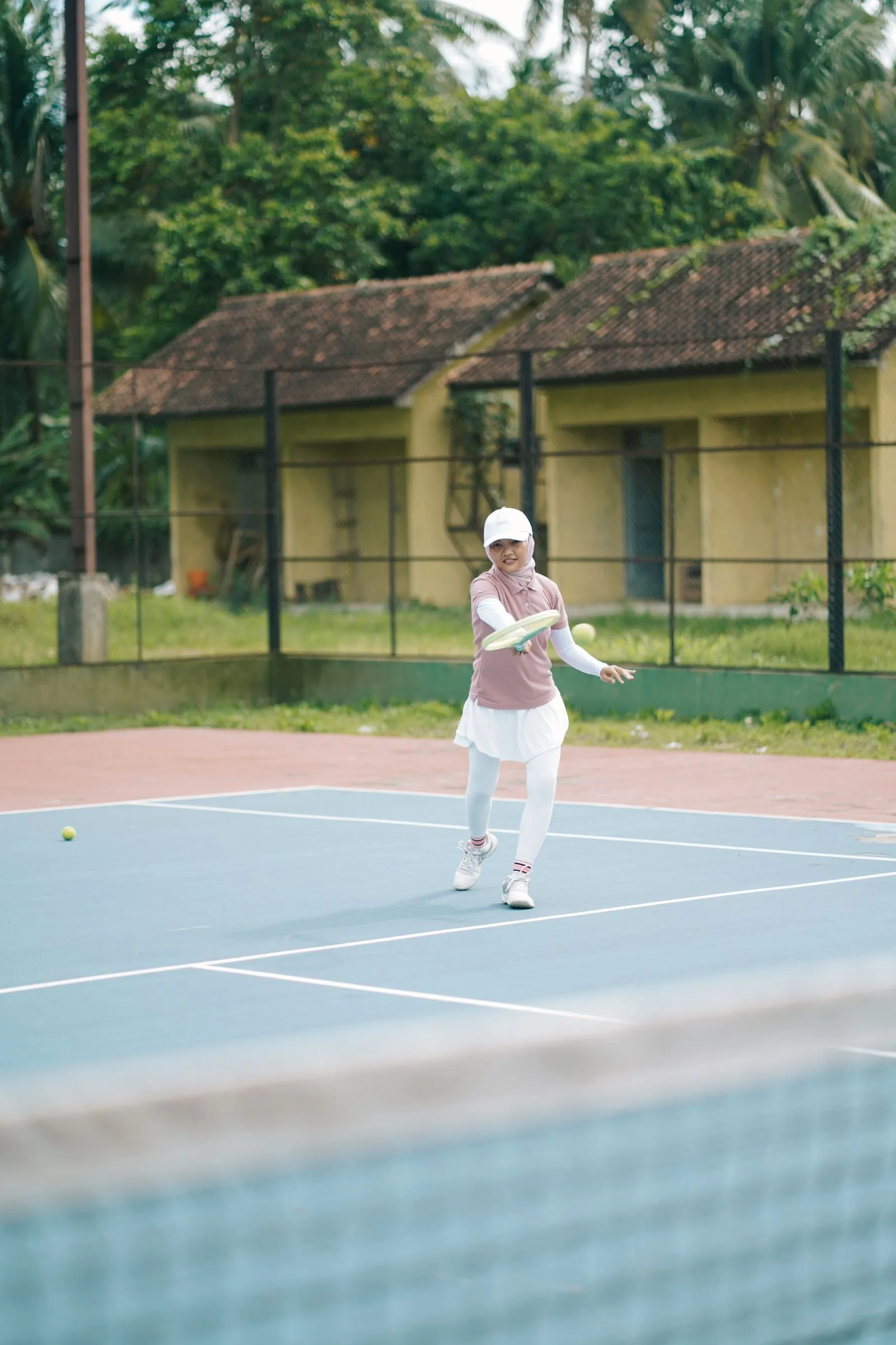 Tennis player in plain kit playing a forehand on an outdoor court