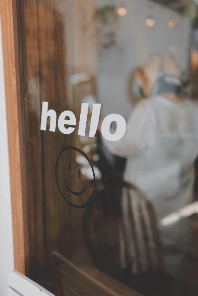Small 'hello' text and smiley face vinyl decal on a cafe window