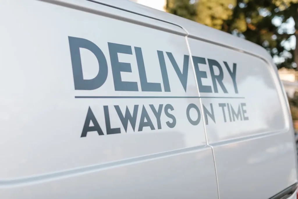 Cut vinyl lettering reading 'Delivery, Always On Time' applied to a van door panel